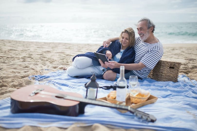 Glückliches Paar beim Picknick am Strand freut sich über Koalitionsvertrag