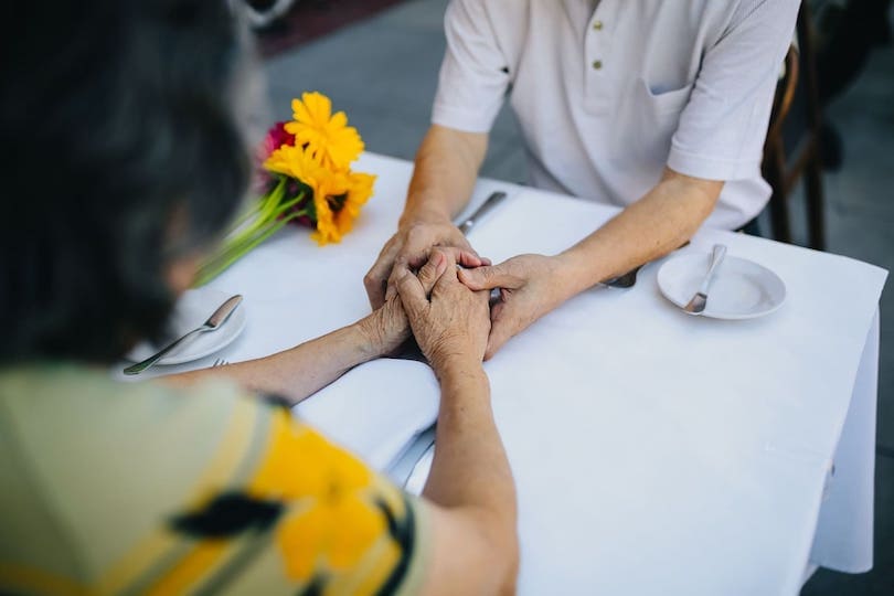 Hände halten mit Blumen am Essenstisch im Krankenhaus nach Notruf
