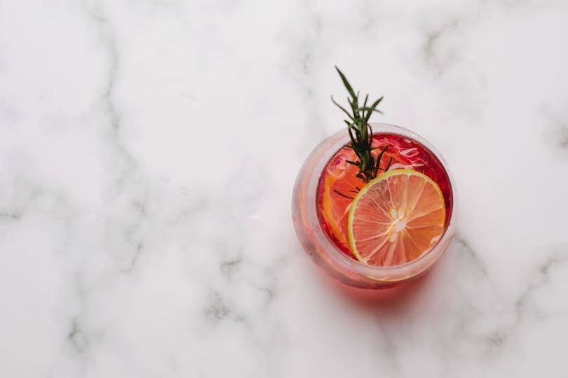 Alkoholischer Cocktail mit Orange und Rosmarin