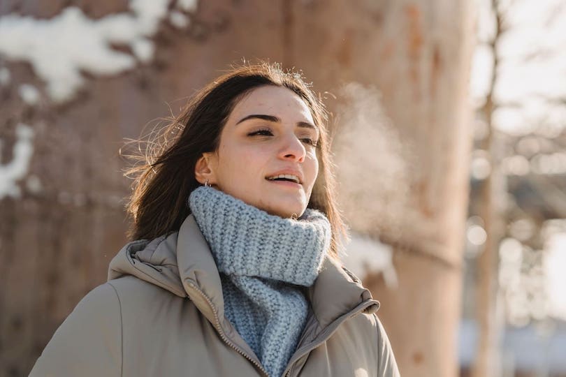 Frau atmet aus im Winter an frischer Luft