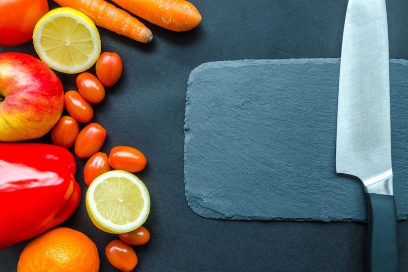 Messer auf Schiefertafel mit Gemüse für gesunde Ernährung im Winter