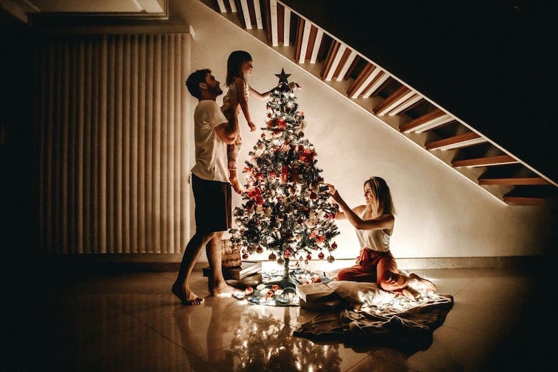 Familie schmückt Weihnachtsbaum mit Weihnachtsgeschenken für Senioren