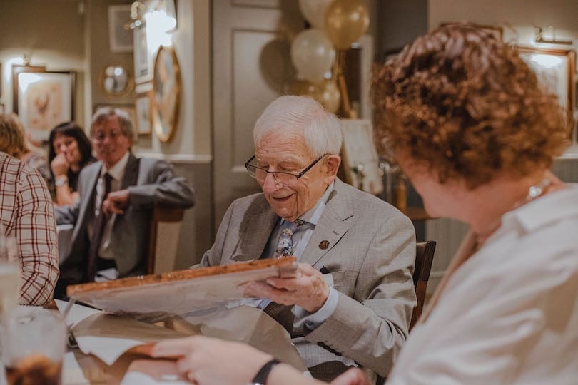Lächelnder Senior mit Brille packt Geschenk aus