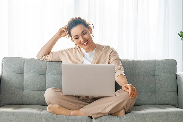 Woman sitting comfortably on her sofa, signing up for Konto.com and earning the $50 Bonus