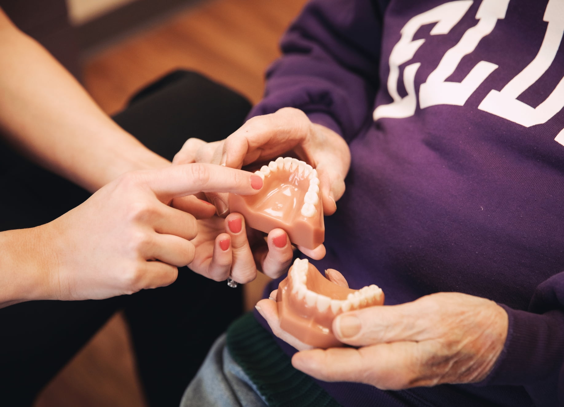 An elderly patient holding a set of dentures