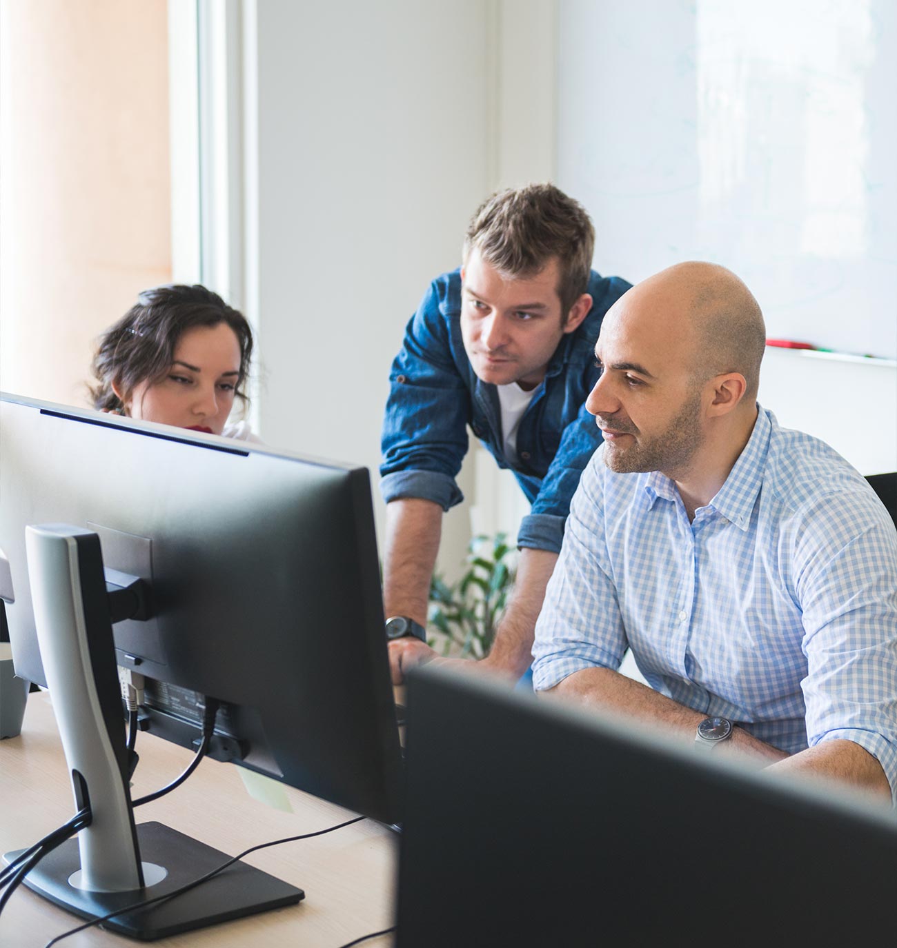 three people at desk looking at computer screen together