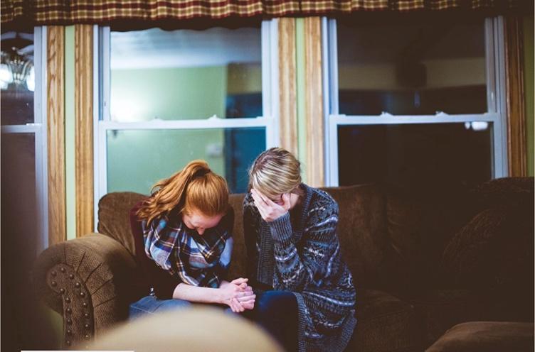 Two women with their heads in their hands dealing with a relationship issue.