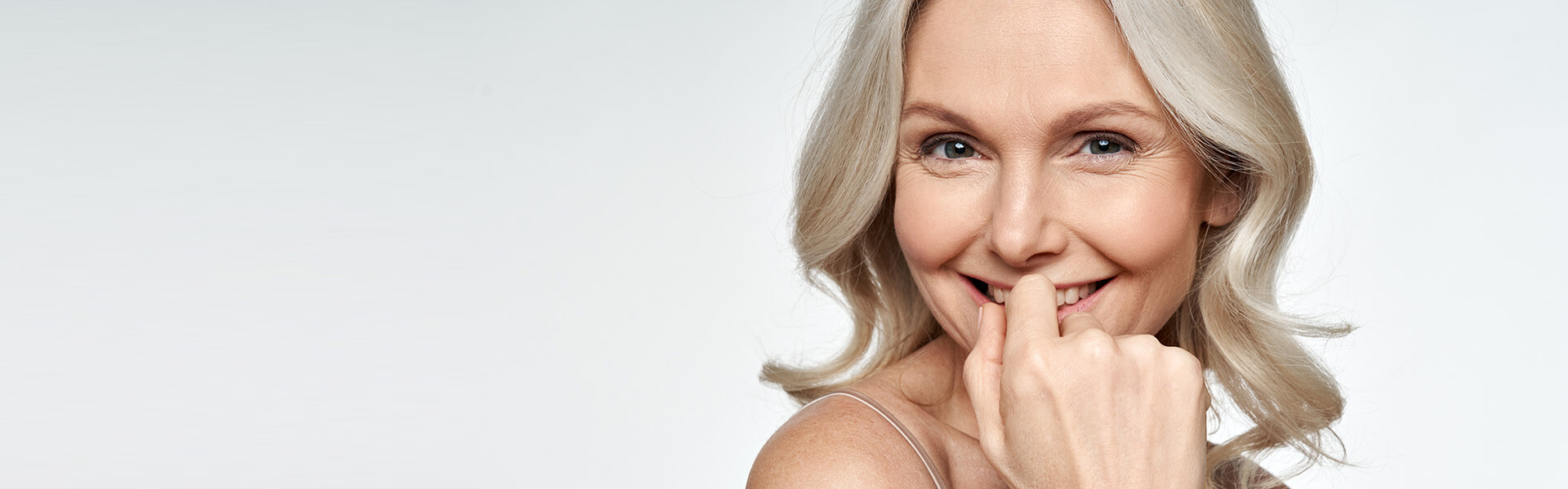 Mature woman with blonde hair smiling with wrinkle-free skin