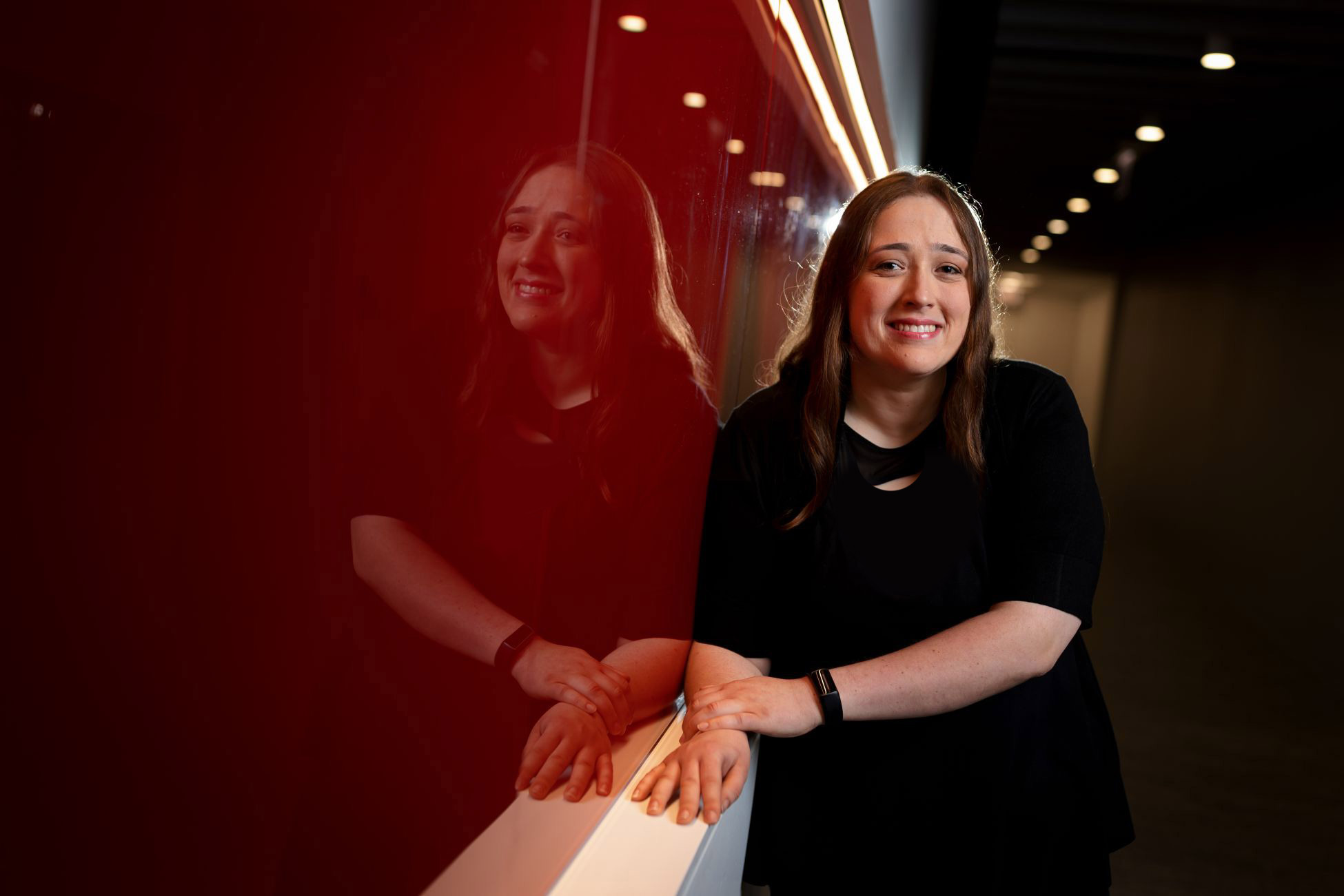 Kara Zukoski smiling next to a red wall