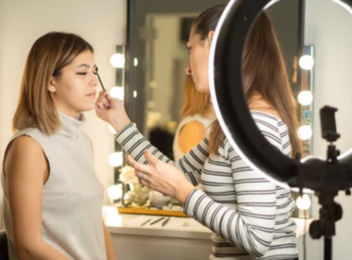 Seorang make up artist yang merias menggunakan bantuan ring light