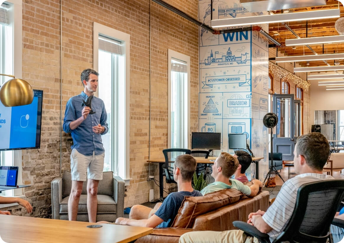 guy giving a pitch in front of co-workers in office