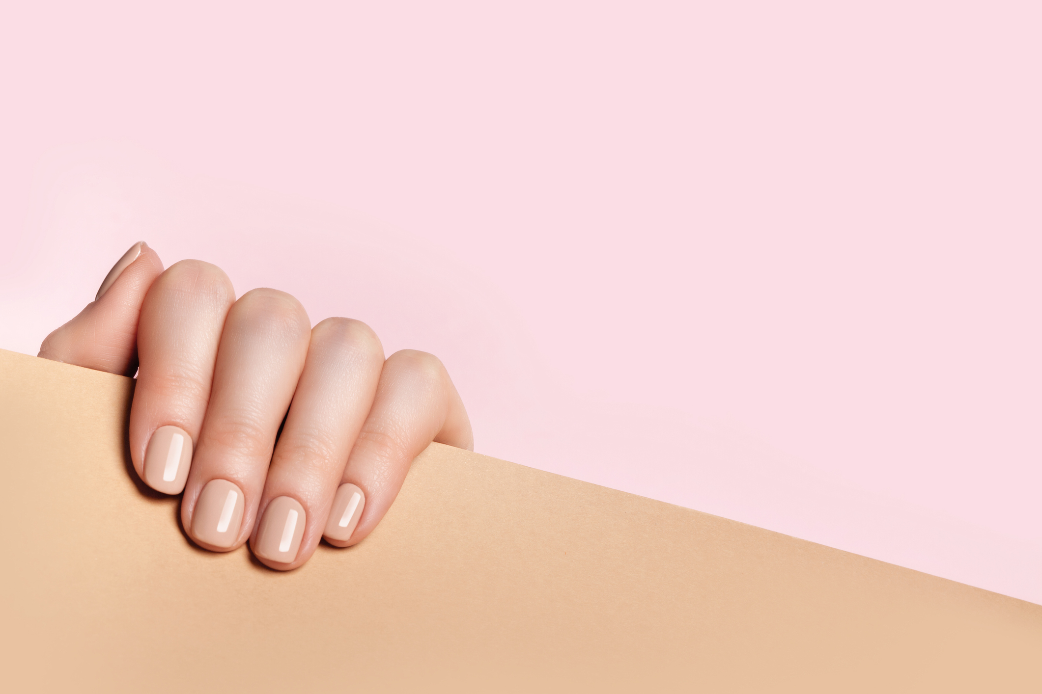 Nude nails on hand with pink background