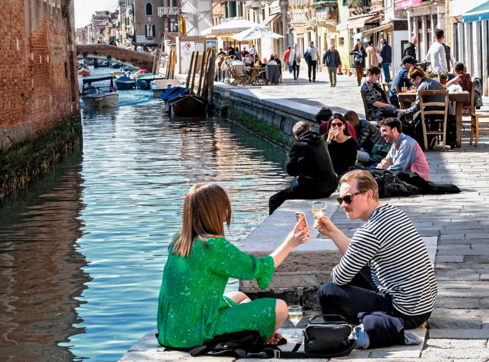 people eating and drinking along canal in Venice.
