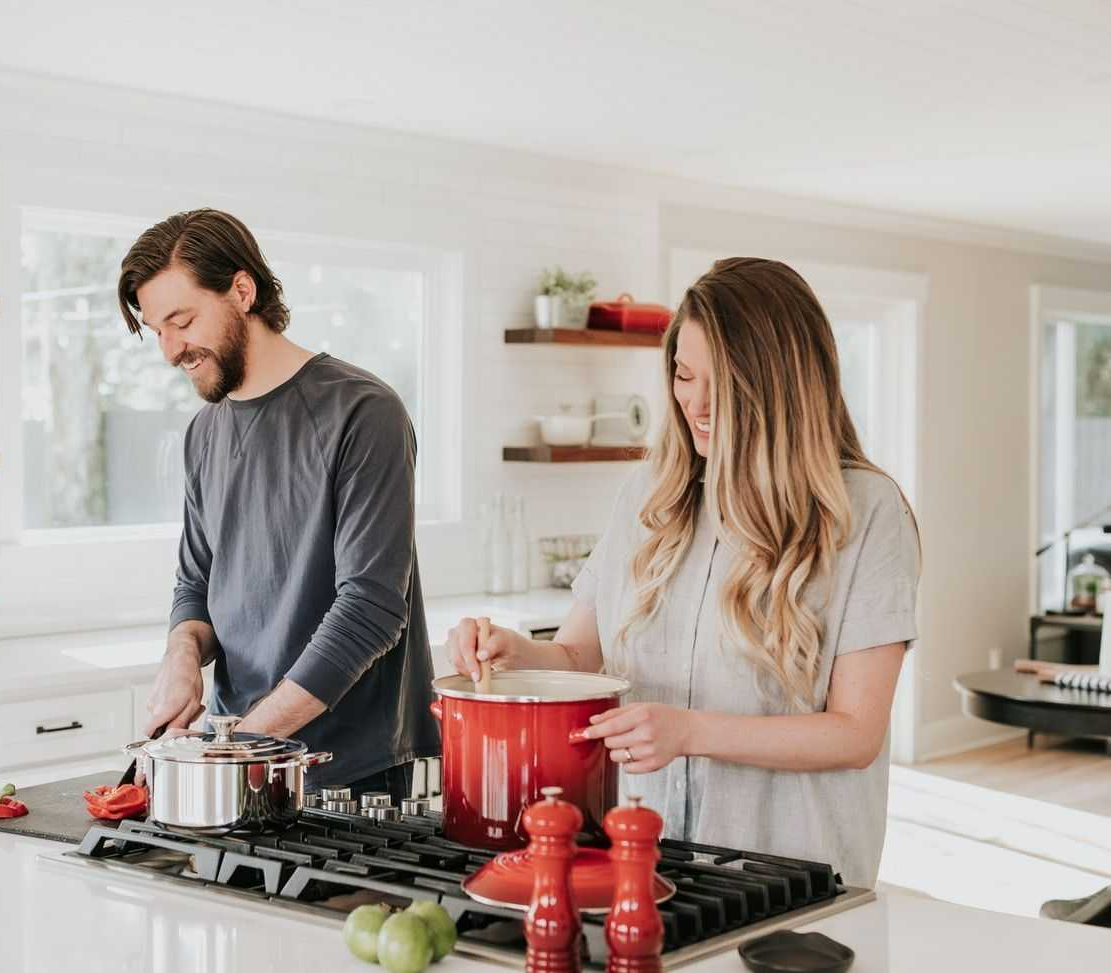 Couple in kitchen cooking in their home looking very happy
