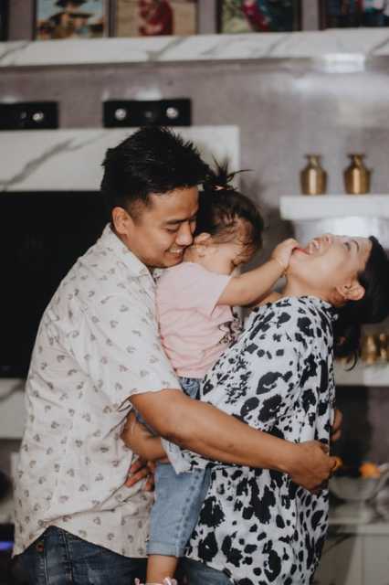 Parents hugging child looking very happy