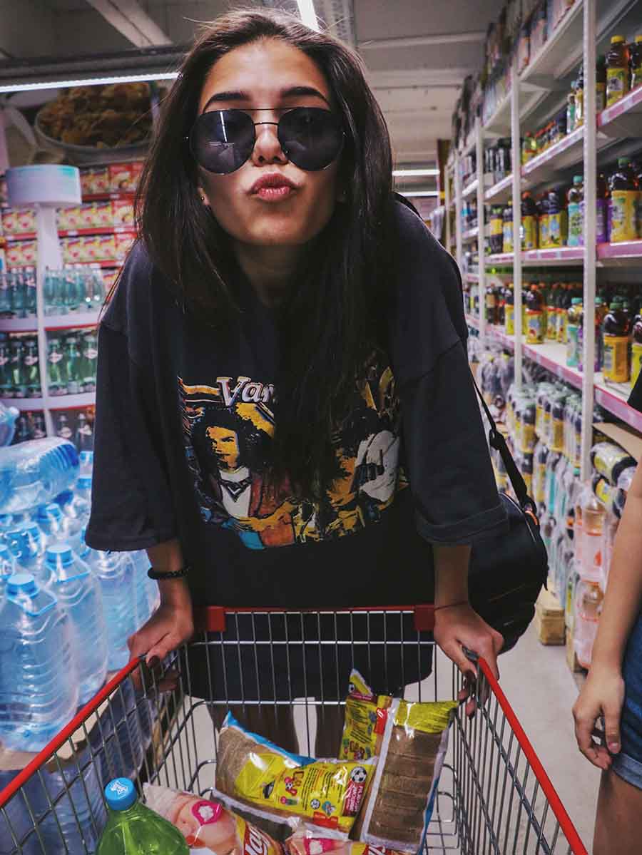 Attractive woman with an attitude riding on the front of a shopping cart in a supermarket