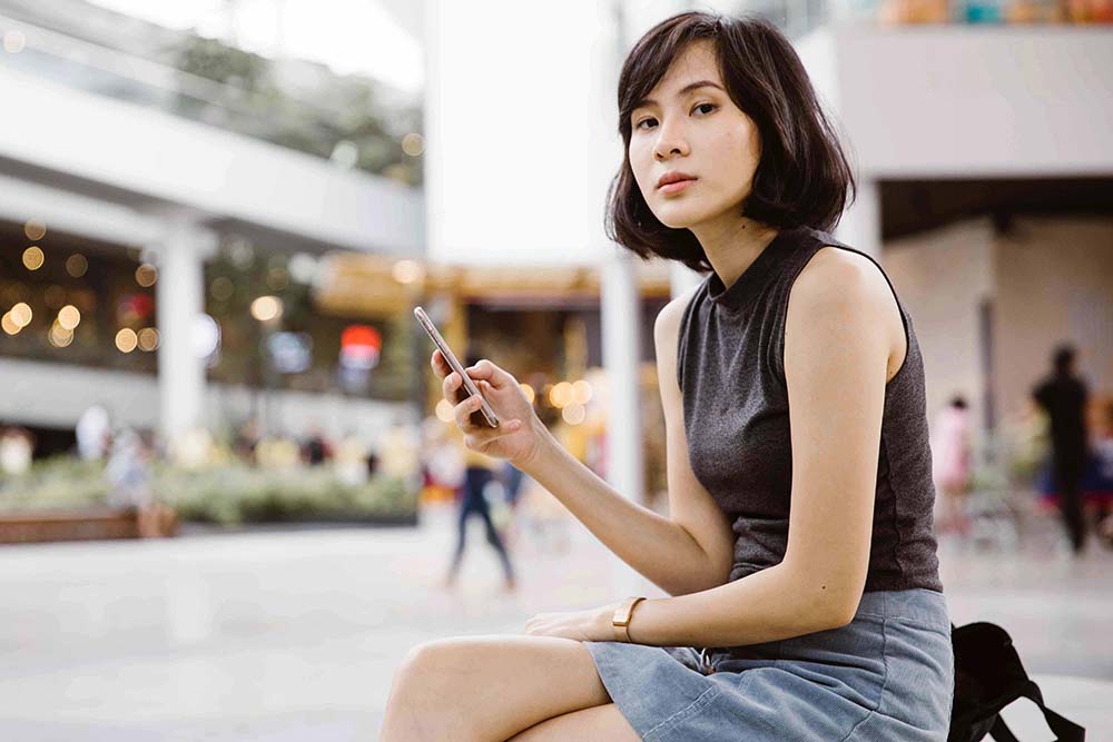 Asian girl sitting in the mall using a mobile phone