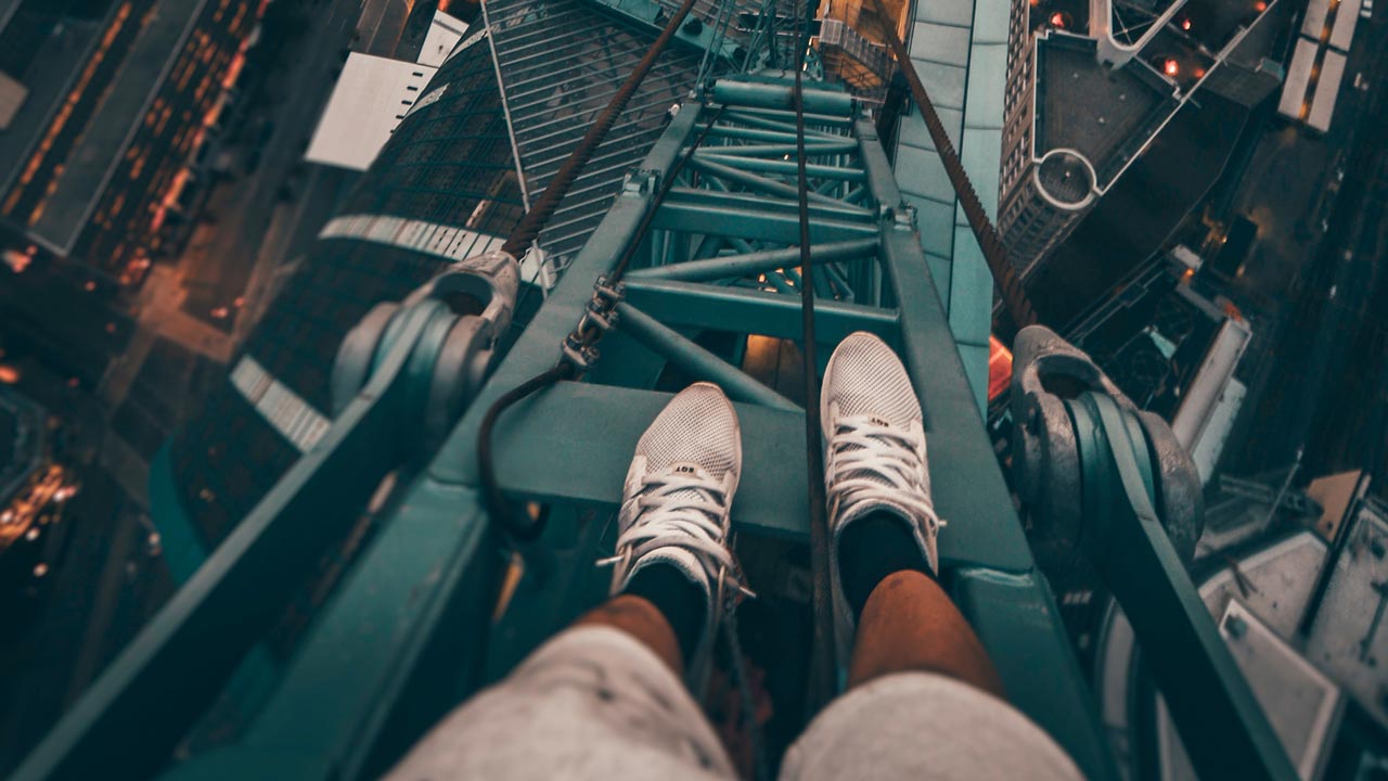 man standing on scaffolding on side of skyscraper