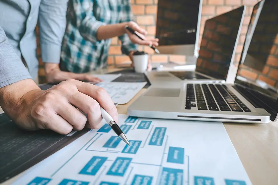 Developers review website wireframes at a large desk.