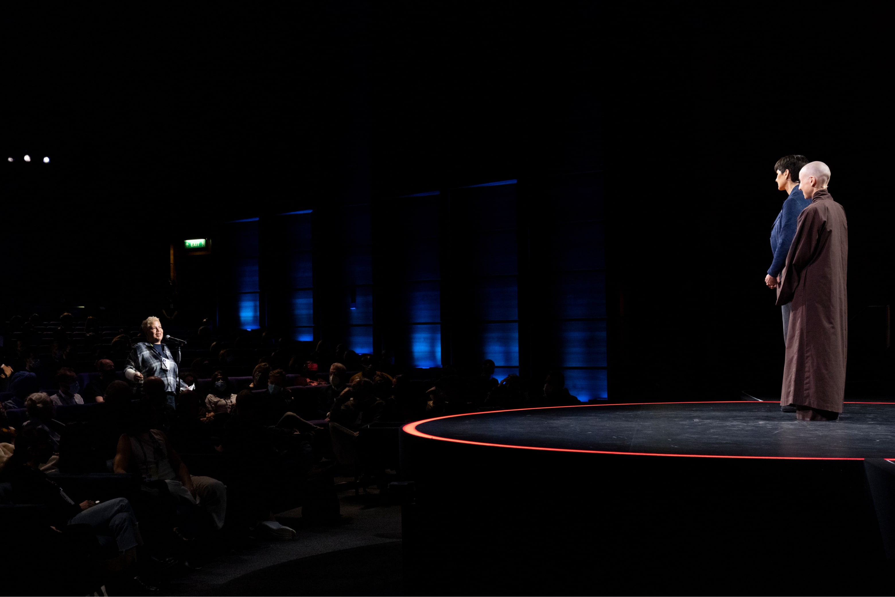 Two speakers listen while a member of the TED Audience asks a question.