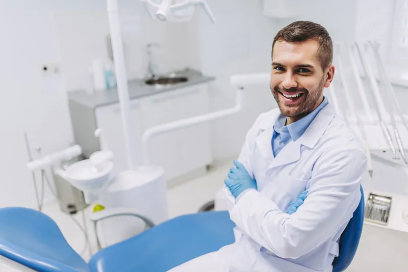 A dentist smiling while inside his dental office.