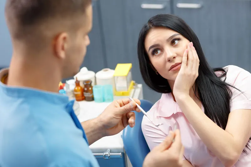 A woman with toothache talking to her dentist.