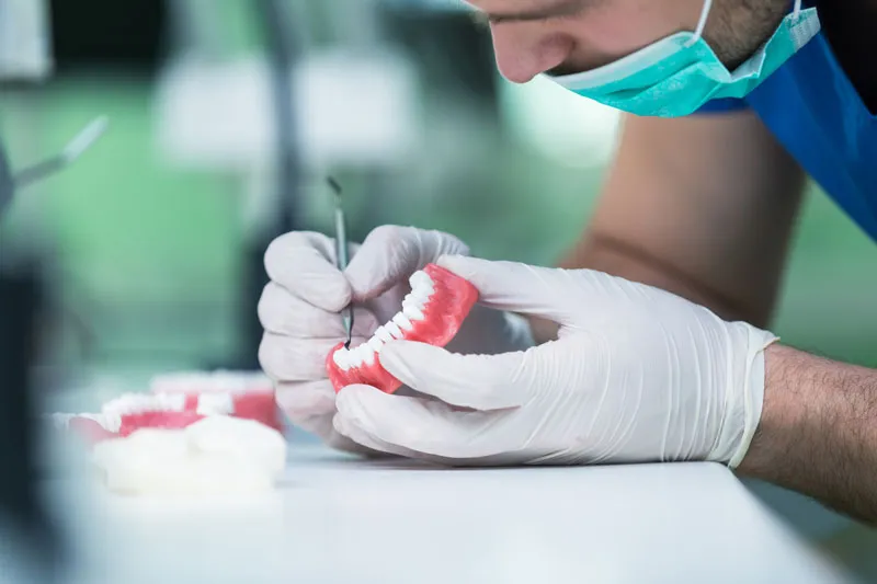 A dentist carefully preparing a denture for his patient.