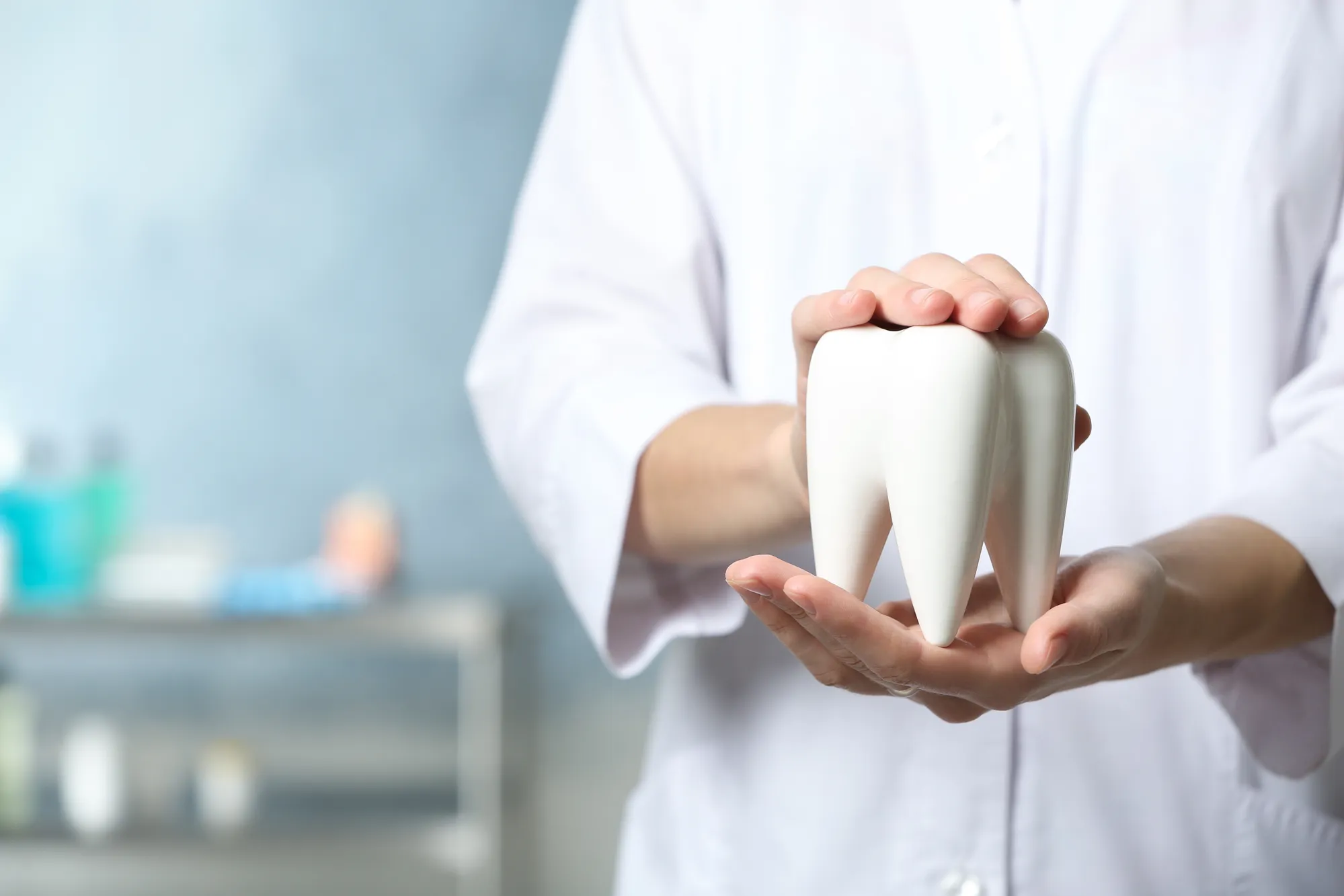 A dentist holding an oversized illustration of a tooth.