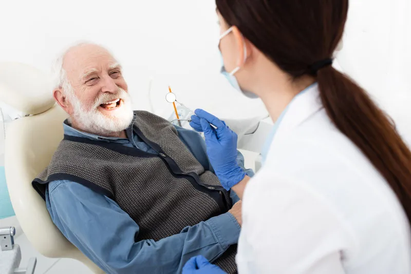 An elderly patient talking to his dentist about his dental health.