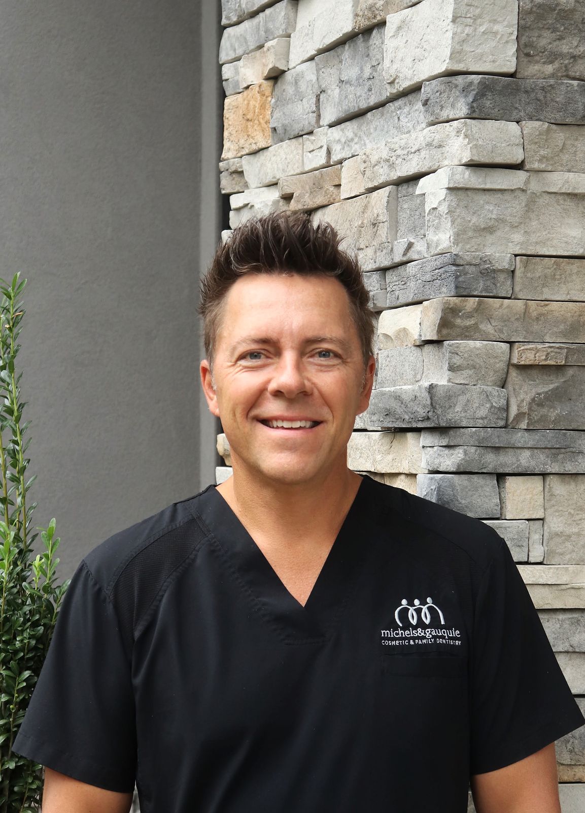 DR. CHRIS GAUQUIE, DDS smiling in front of his dental clinic.
