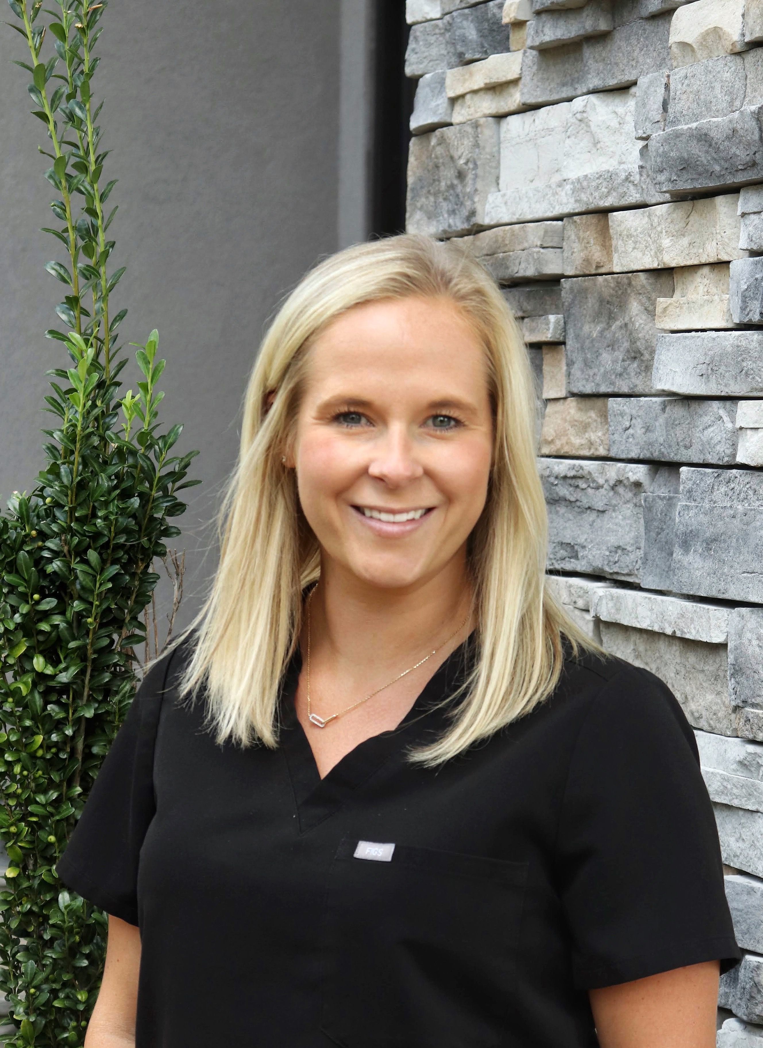 DR. SARAH LANGLEY HARRELL, DMD smiling in front of her dental clinic.
