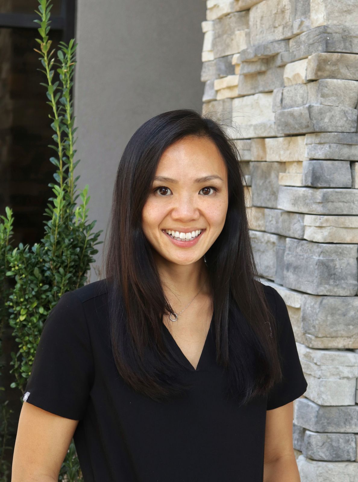 DR. EMILY CHAN, DMD smiling in front of her dental clinic.