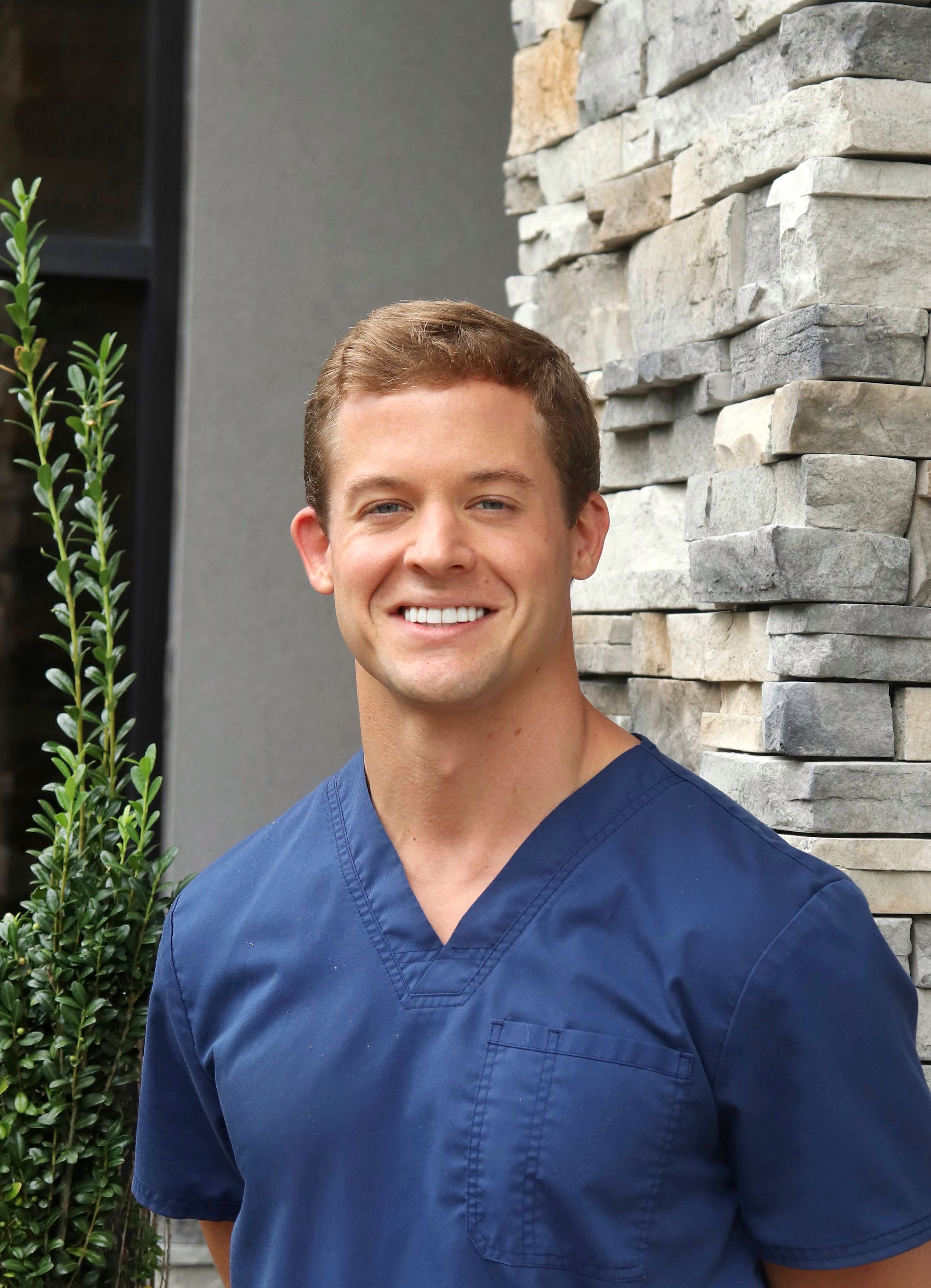 DR. AUSTIN MICHELS, DMD smiling in front of his dental clinic.