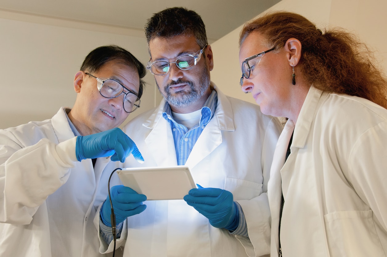 Three scientist looking at a small screen.