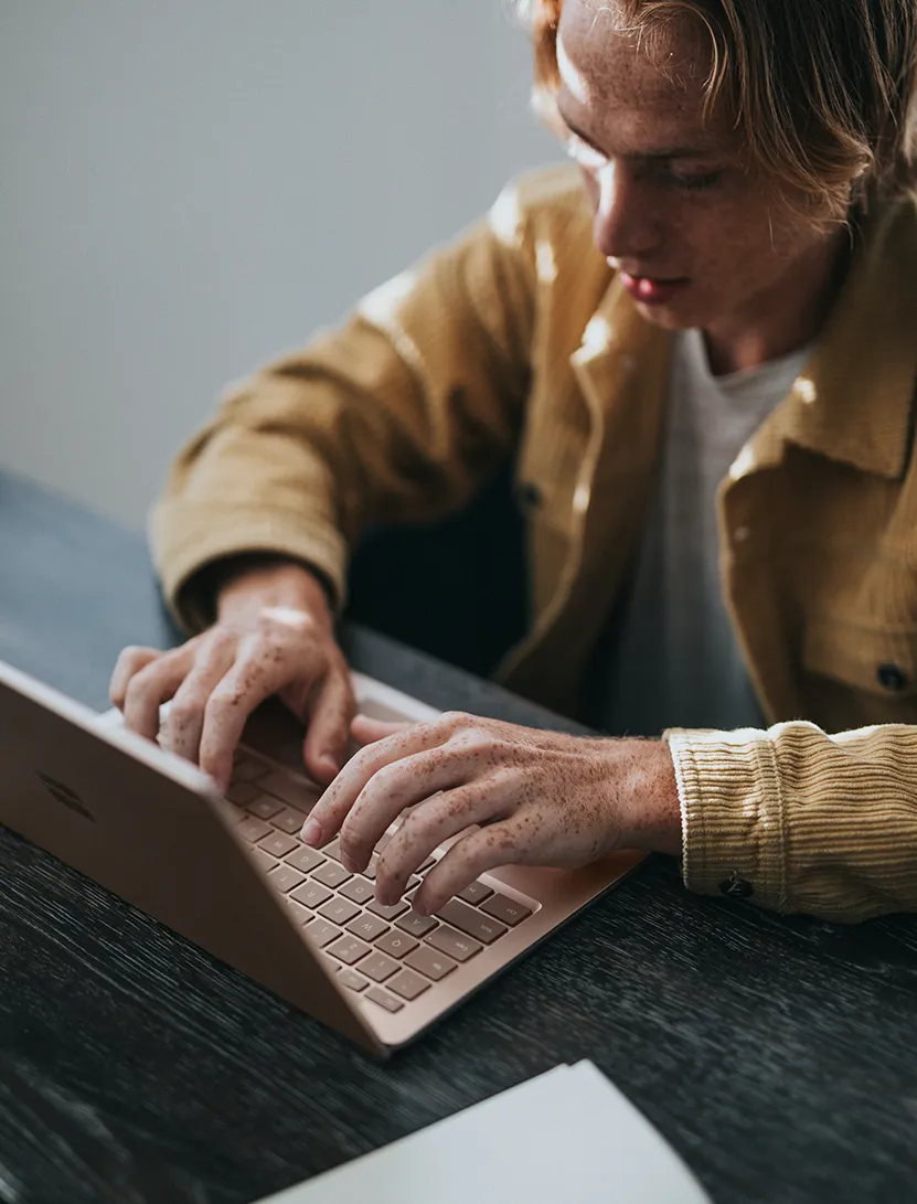 Junger Mann tippt auf Microsoft Surface Laptop.