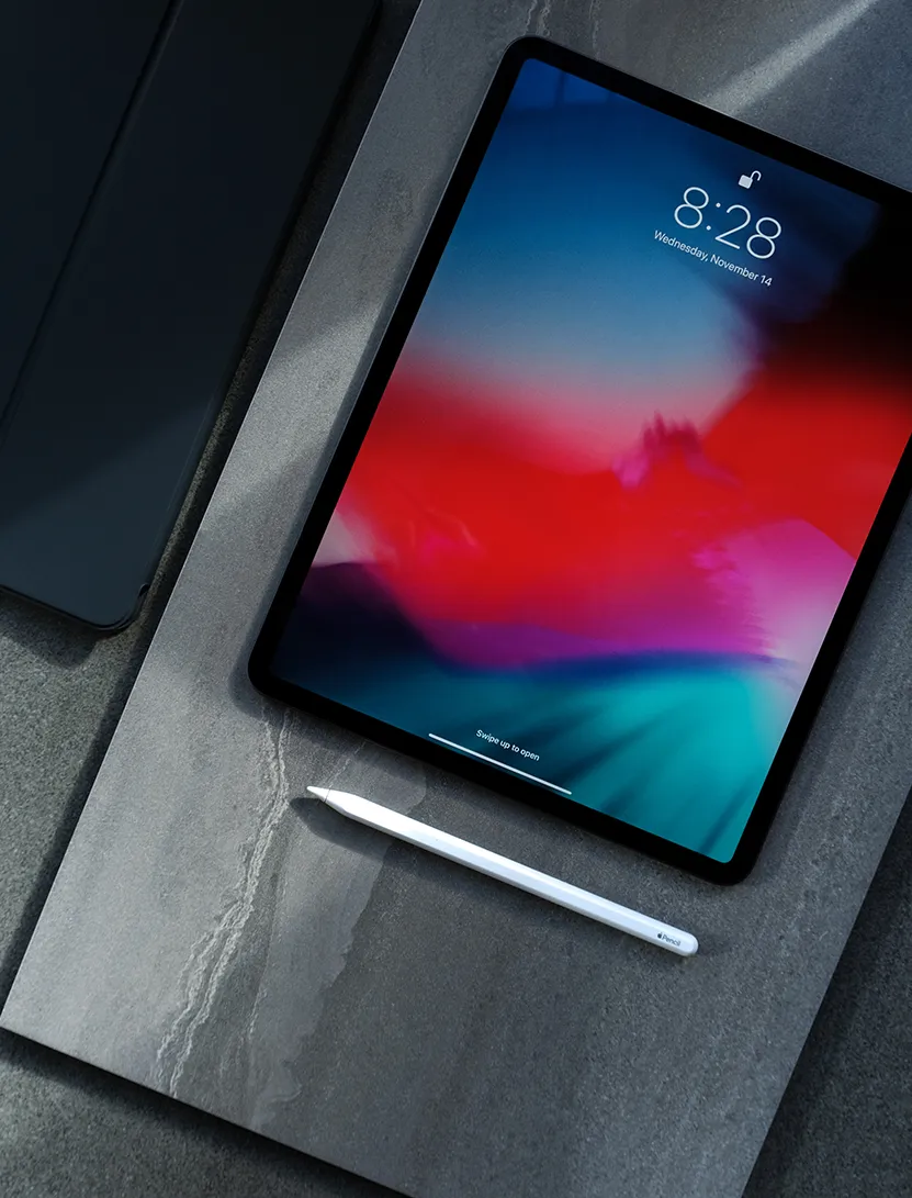 Apple iPad Pro mit Apple Pencil liegt auf Steinplatte. Daneben ein weiteres iPad mit Cover.