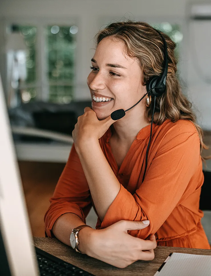 Frau sitzt im Home Office am Schreibtisch und telefoniert mit Headset