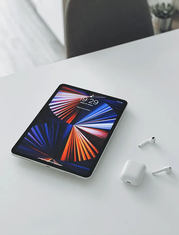 iPad Pro und AirPods liegen auf einem weißen Tisch.