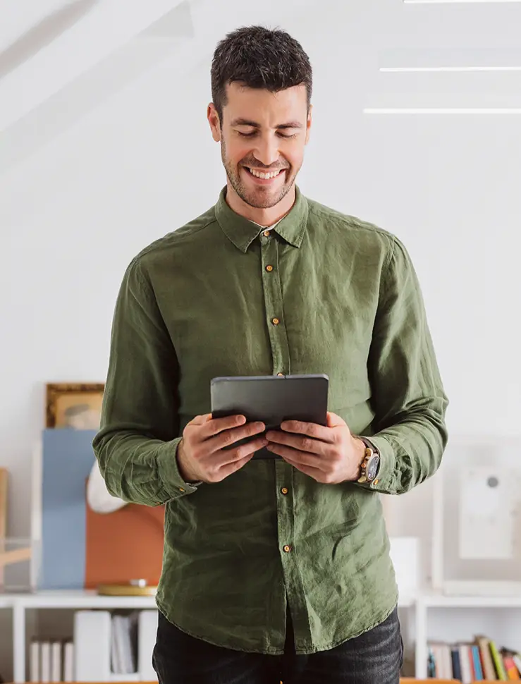 Lächelnder Mann in einem grünen Hemd mit einem digitalen Tablet-PC im Büro