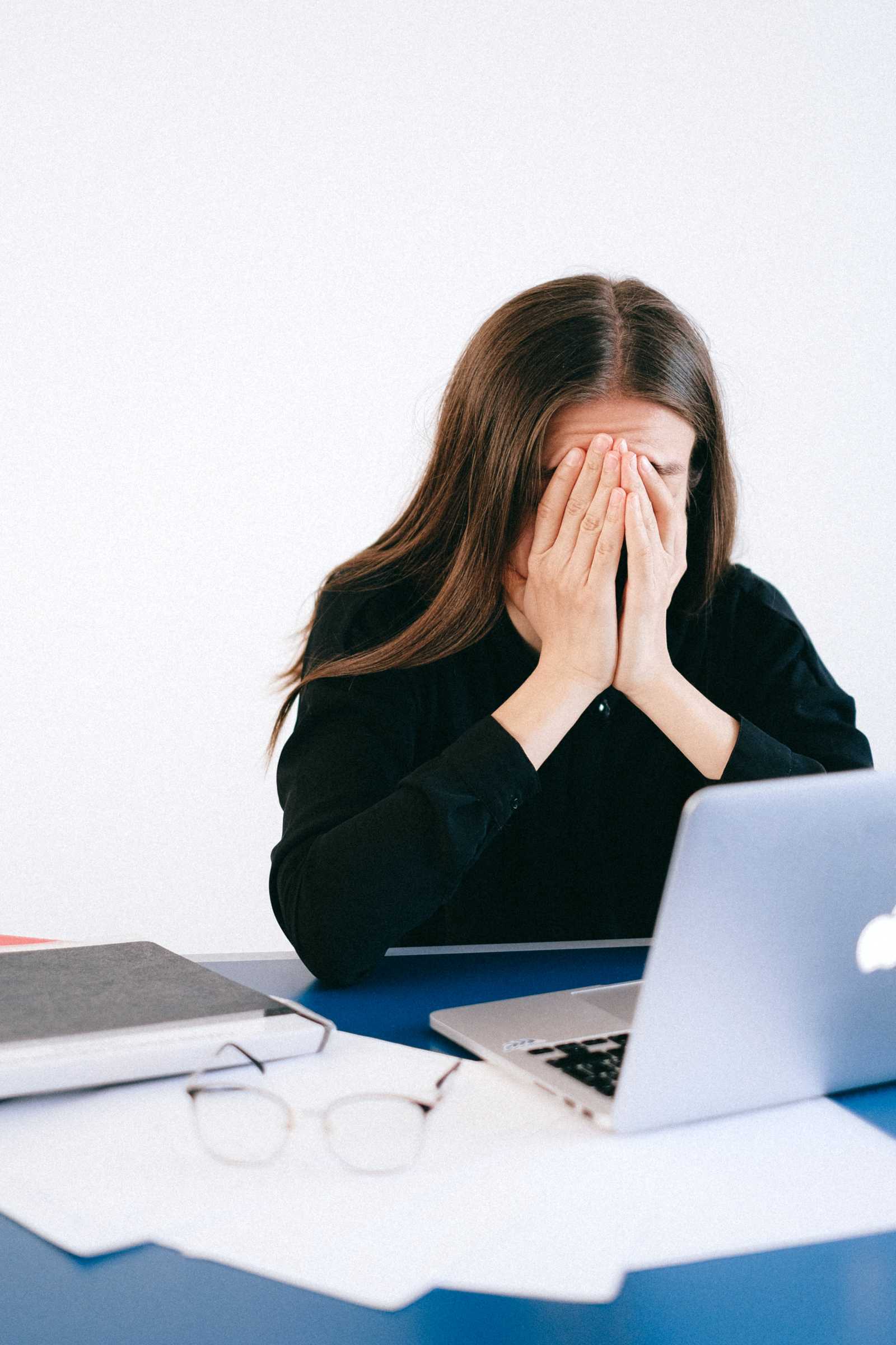 Upset woman with her head in her hands while sitting at her desk