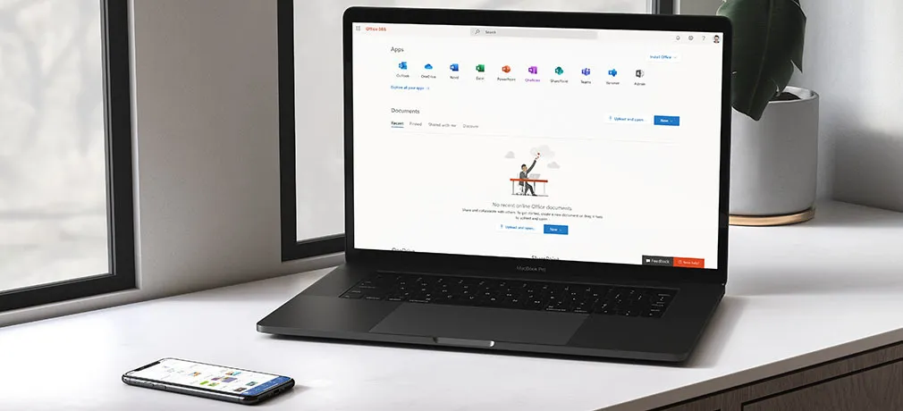 Ein MacBook und iPhone liegen auf der Fensterbank und zeigen Office 365 auf dem Display.