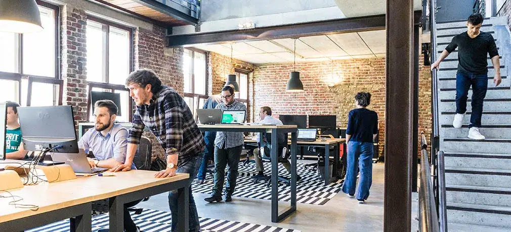 Ein modernes Büro im industriellen Stil mit mehreren Arbeitsplätzen und Personen.