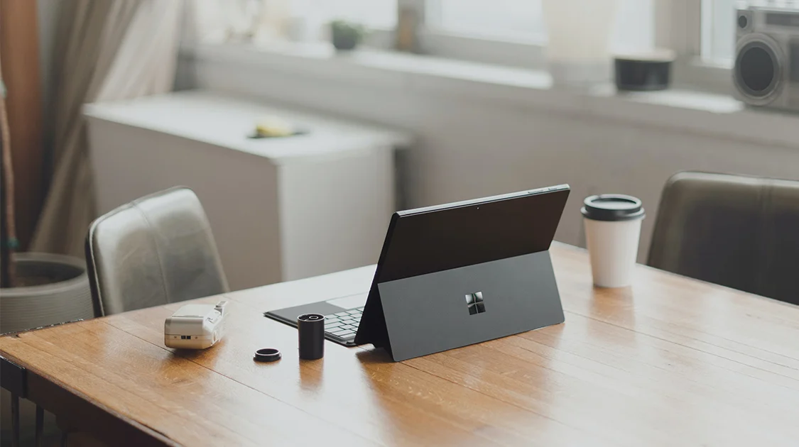 Arbeitsplatz am Tisch mit Surface Pro, Kamera und Kaffebecher