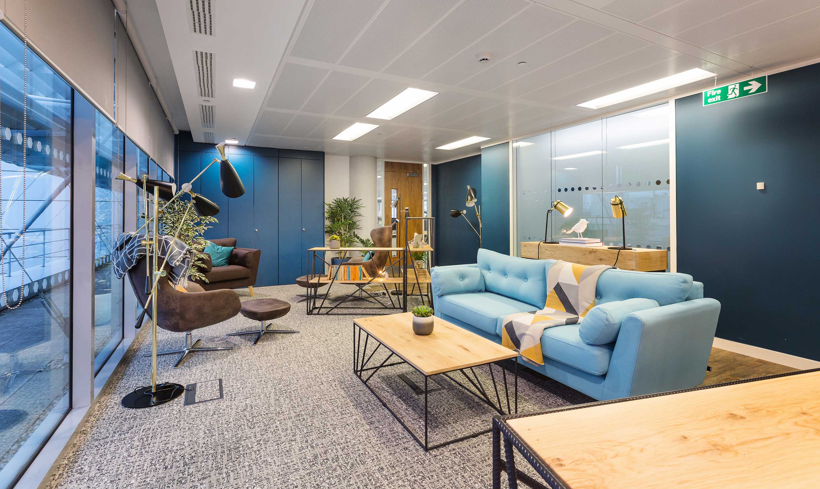 stylish office interior with large blue sofa and wooden tables