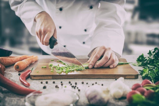A chef chopping green onions and other vegetables.