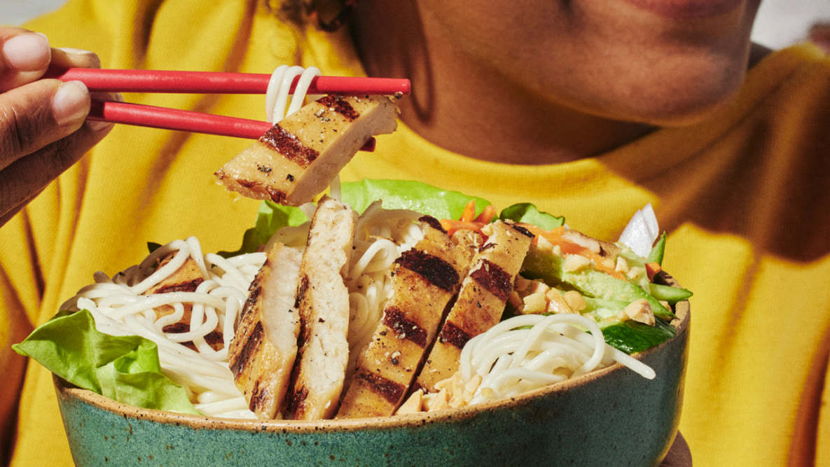 bowl of chicken and pasta eaten with red chopsticks