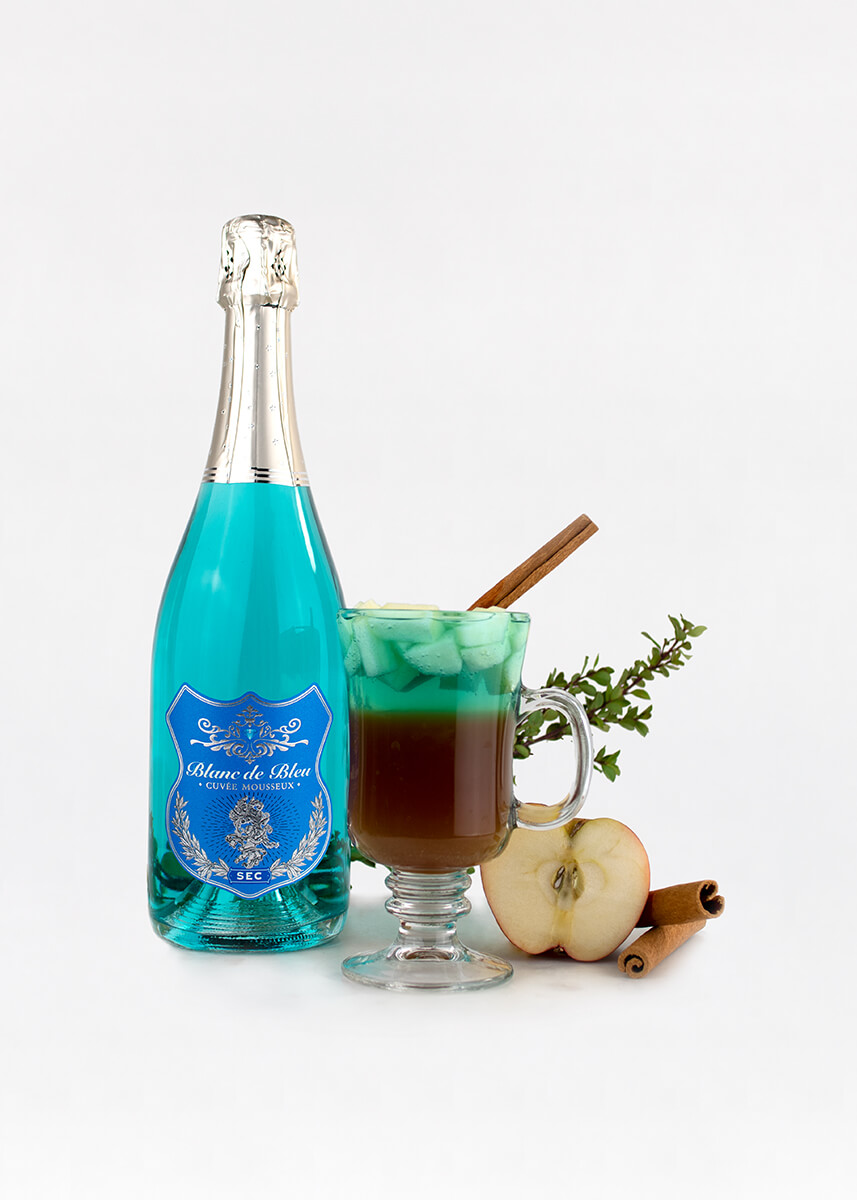 An "Autumn Lake" cocktail and a bottle of Blanc de Bleu Sec, next to half an apple and cinnamon sticks