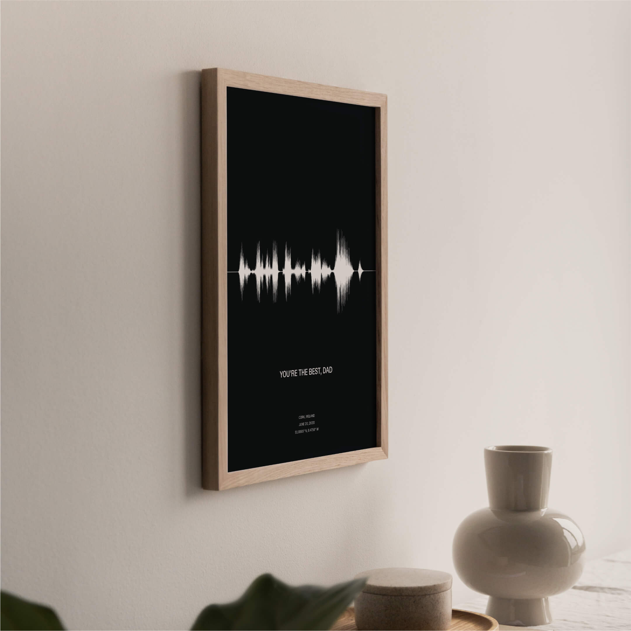 A black poster inside a natural finish wood frame. The poster depicts a sound-wave of the phrase "you're the best, dad". Recorded for father's day and includes an audio caption, location and date of the recording.