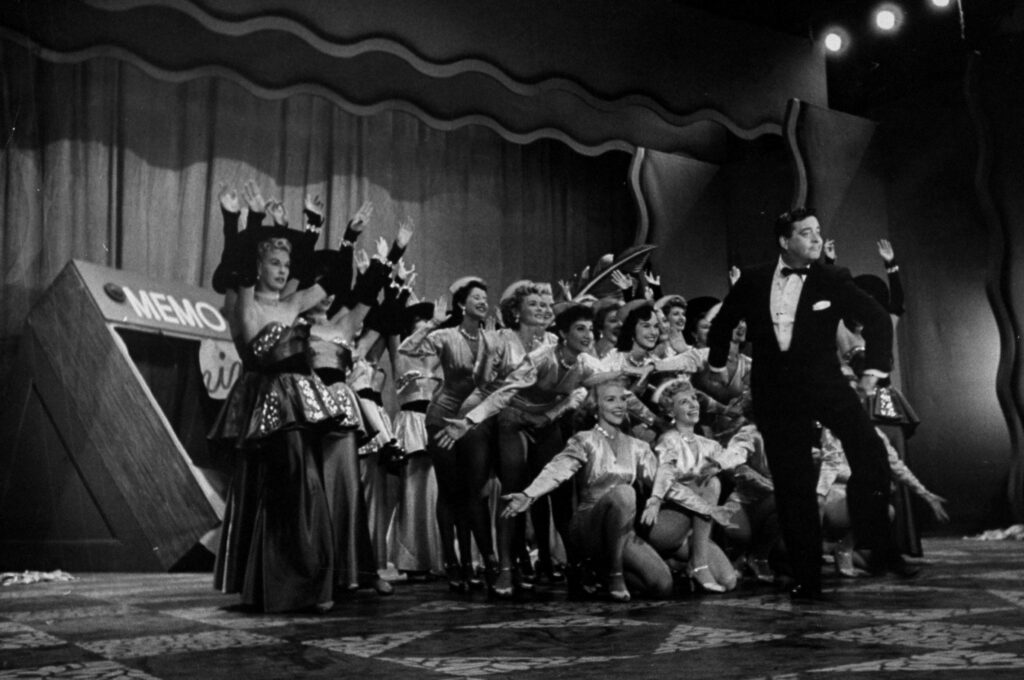 Jackie Gleason performing with a bunch of chorus girls.