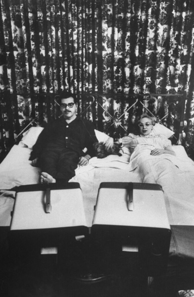 A couple watching TV on two televisions.